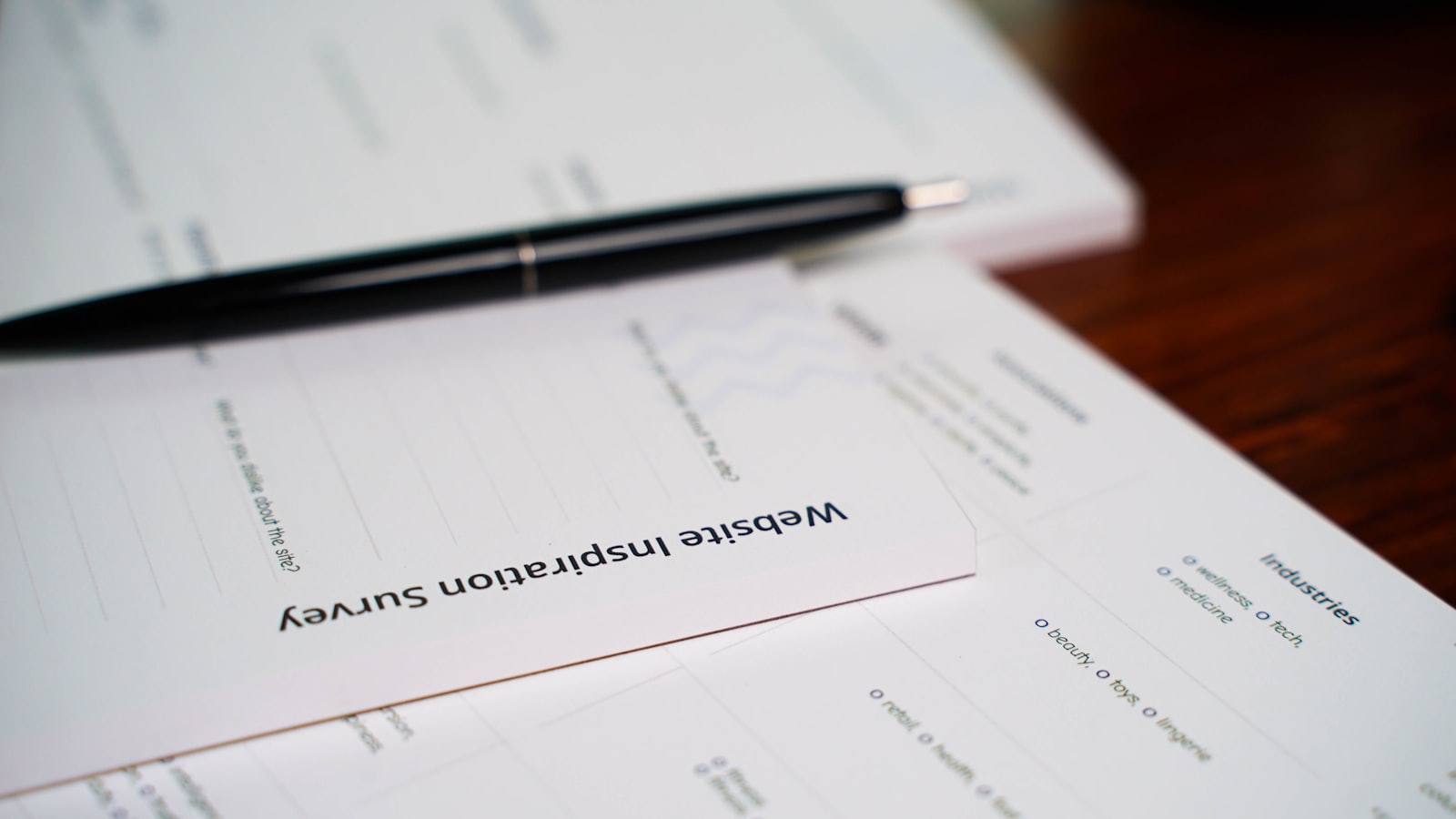 A tidy stack of export trade documents — a commercial invoice and packing list — spread on a desk beside a pen.