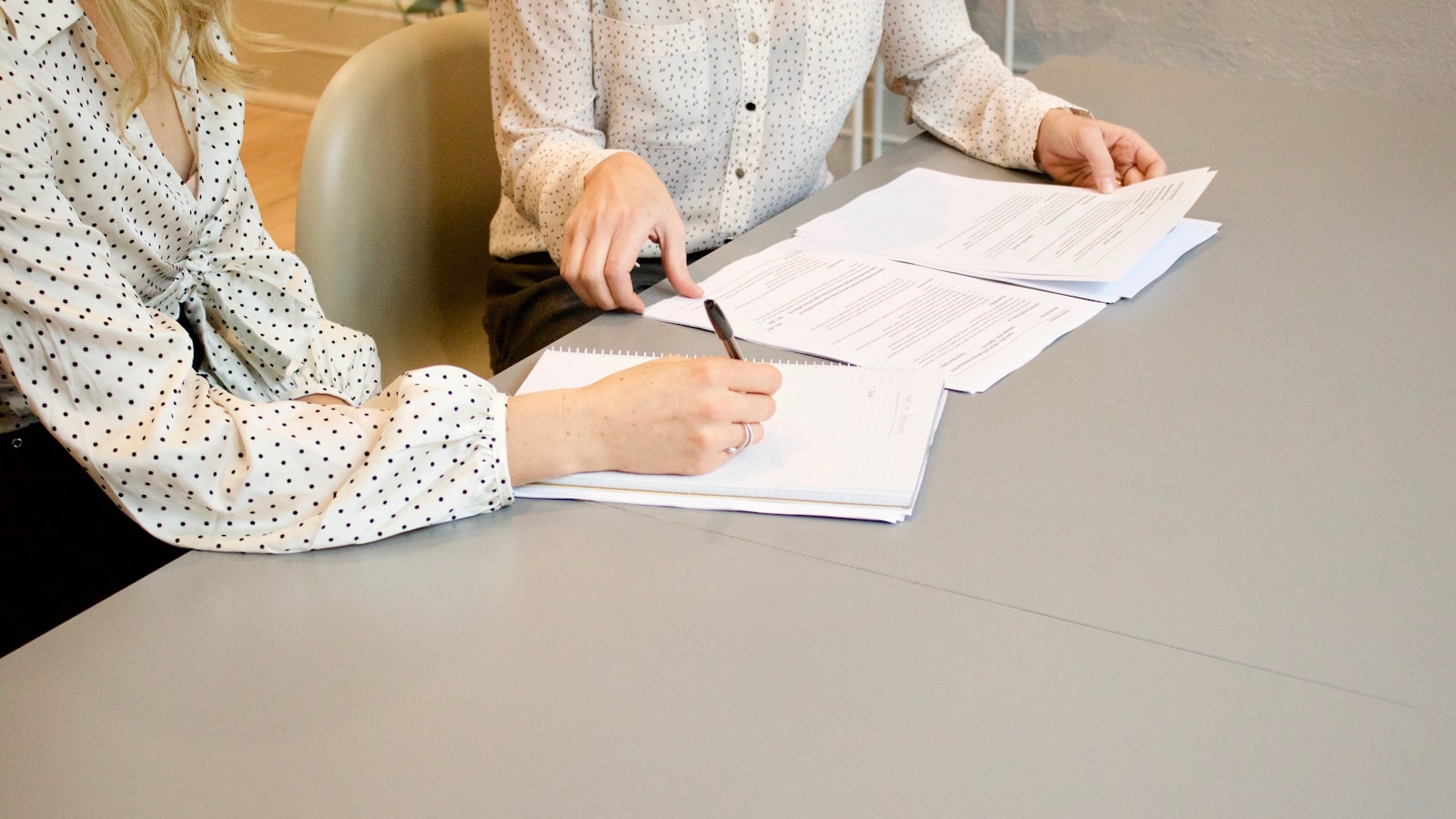 Hands signing a printed document on a desk.